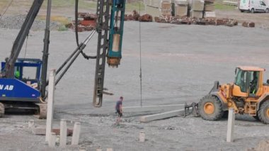 Man prepares piles for driving into ground with pile driver machine. Sweden. Enkoping. 05.08.2022