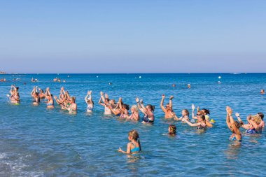 Beautiful view of group of tourists doing water dancing in on coastline of Mediterranean sea. Rhodes. Greece. 07.15.2022. 