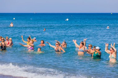 View of group of tourists doing water dancing in on coastline of Mediterranean sea. Rhodes. Greece. 08.20.2022. 