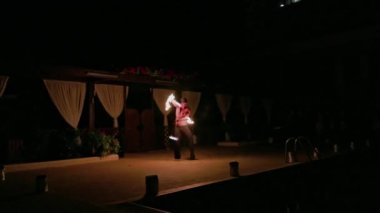Beautiful view of performance of man working with nunchaku, at evening fire show in front of tourists. Rhodes. Greece. 07.12.2022.