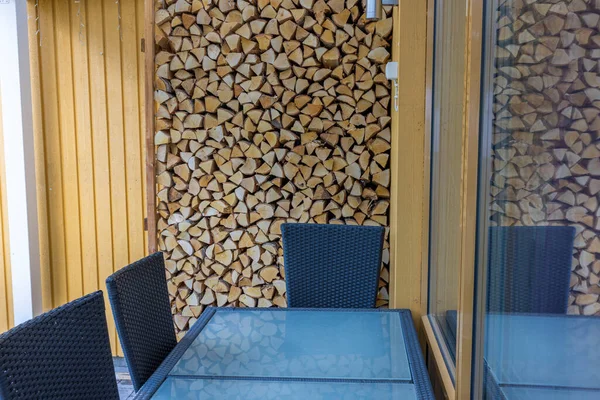Beautiful view of outdoor furniture near folded stack of birch firewood. Sweden.