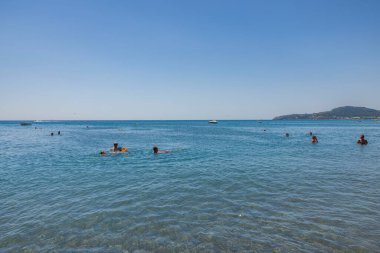 Güneşli yaz gününde denizde yüzen güzel manzaralı insanlar. Rodos. Yunanistan. 07.15.2022