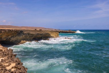 Mavi arka plandaki kayalık kıyı şeridindeki büyük dalgaların muhteşem manzarası. Aruba. 