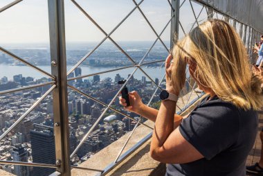  Empire State Binası 'ndan Manhattan' ın video kamerasıyla çekim yapan bir kadın. New York, ABD.