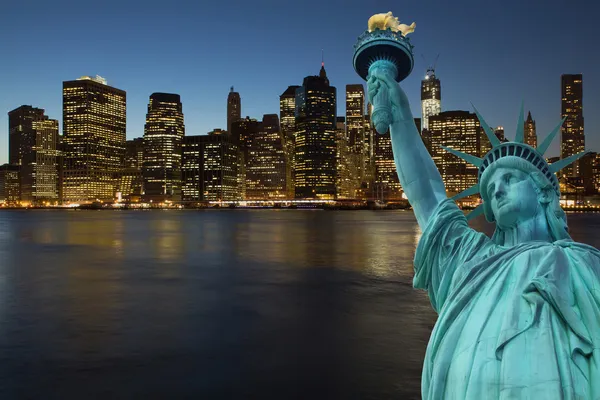 Lower Manhattan at night with Statue of LIberty Stock Photo