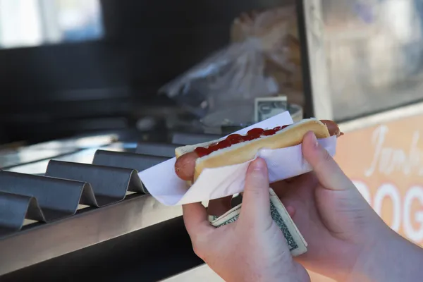 Customer holding a hot dog purchased. — Stock Photo, Image