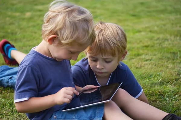 A szőke fiú játszik szabadtéri tablet pc. — Stock Fotó