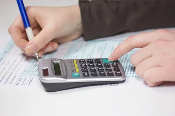 Einkommensteuerformulare mit Taschenrechner und Stift ausfüllen — Stockfoto