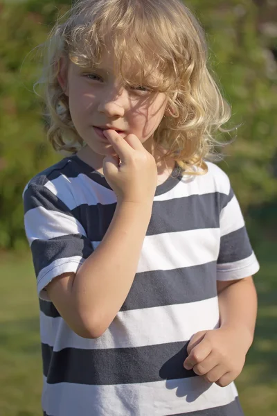 The blond boy is biting his nails. — Stock Photo, Image