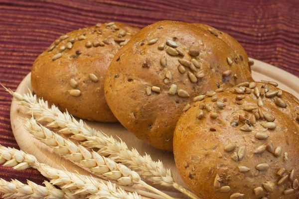 Wholemeal bread with wheat ears on the table. — Stock Photo, Image