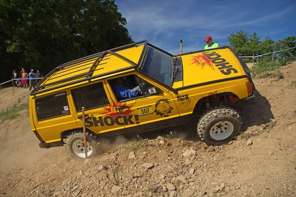 Carro offroad amarelo está batendo em uma colina íngreme — Fotografia de Stock