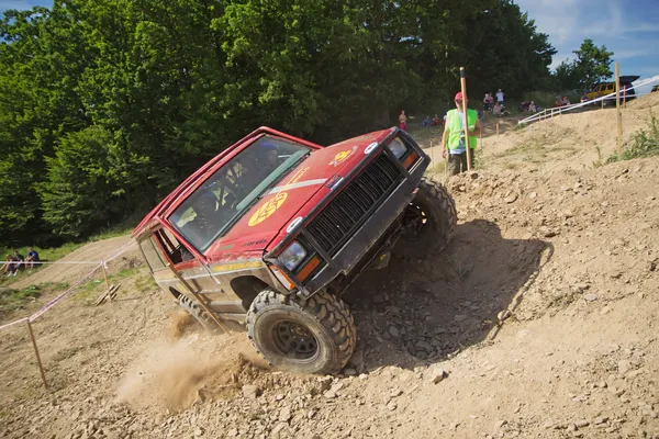 Offroad czerwony samochód jest w wielkim pochylenia bocznego — Zdjęcie stockowe