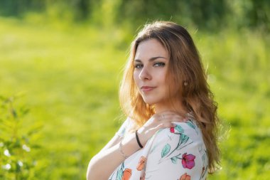 Çekici, güzel genç bir kadın dışarıda poz veriyor. Yatay olarak. 