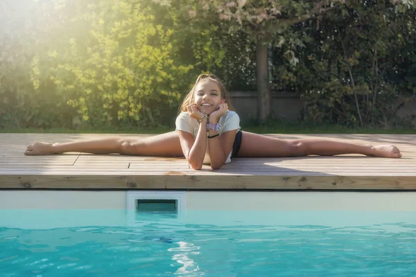 Şirin esnek bronzlaşmış kız havuz kenarında jimnastik yapıyor. Yatay olarak. 