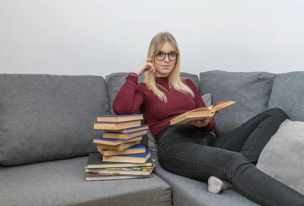 Young Woman Sitting Couch Reading Book Leaning Pile Books — Foto de Stock