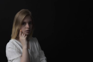 Low key portrait of serious young woman looking at the camera. Horizontally.
