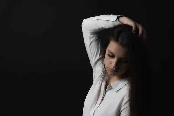 Low key portrait of sad young woman weared in white shirt.