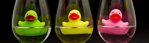 Green, yellow and pink rubber ducks in wineglasses — Stock Photo, Image