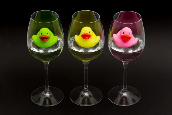 Patos de goma verdes, amarillos y rosados en gafas de vino — Foto de Stock