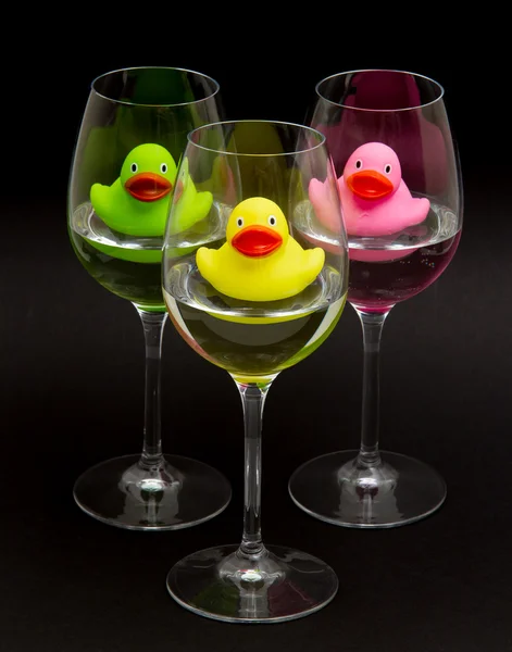 Patos de goma verdes, amarillos y rosados en gafas de vino — Foto de Stock