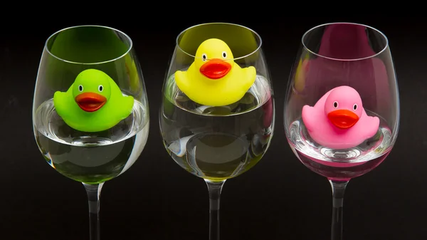 Patos de goma verdes, amarillos y rosados en gafas de vino — Foto de Stock