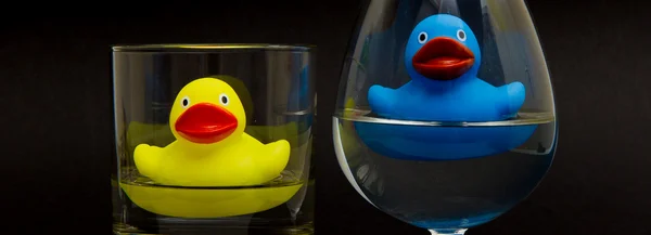 Blauwe en gele rubberen eend in glazen — Stockfoto
