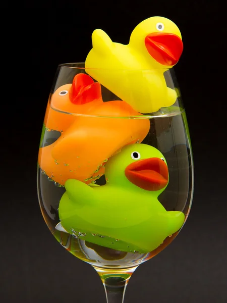 Canard en caoutchouc jaune, orange et vert dans un verre à vin — Photo