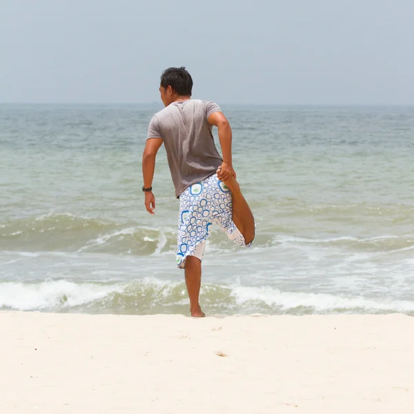 Uomo che si estende sulla spiaggia a sud del mare cinese — Foto Stock