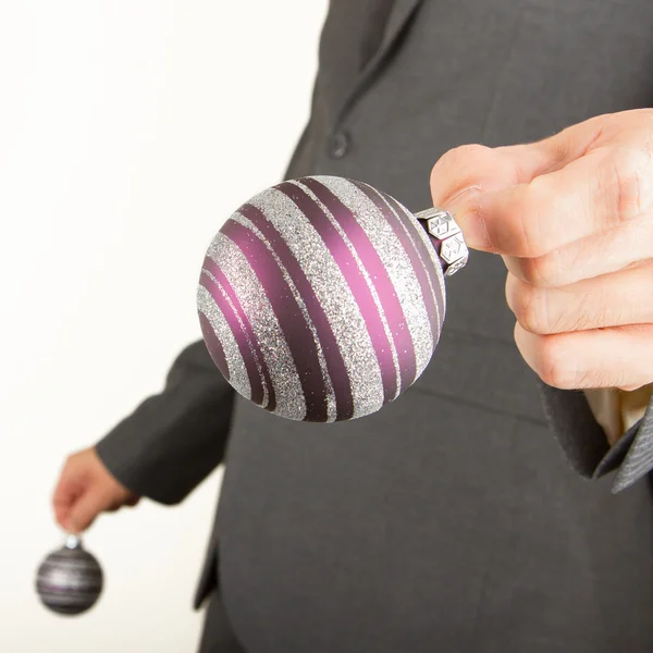 L'homme en costume gris tient des boules de Noël — Photo