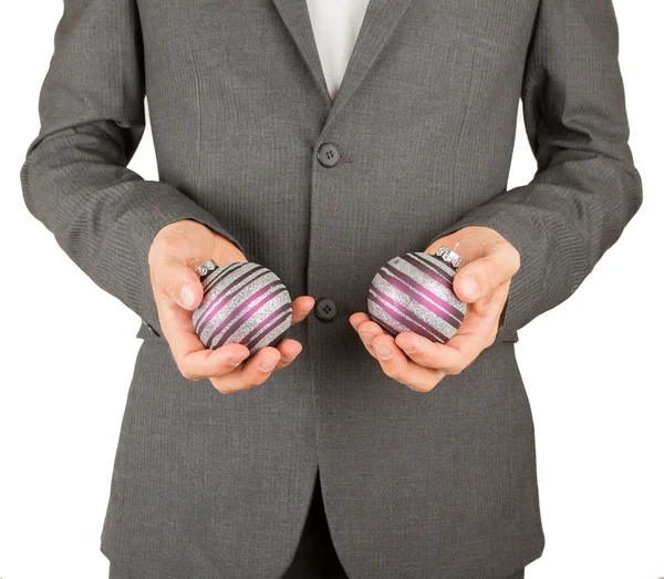 Hombre en traje gris sostiene bolas de Navidad — Foto de Stock