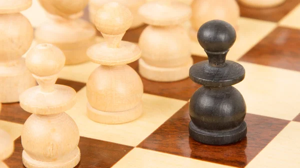 Black pawn on a wooden chessboard — Stock Photo, Image