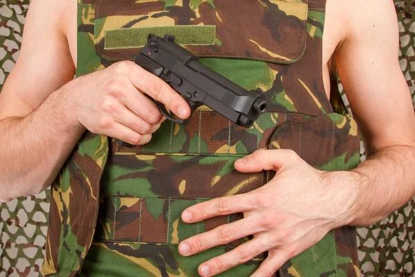 Soldier in camouflage vest is holding a gun — Stock Photo, Image