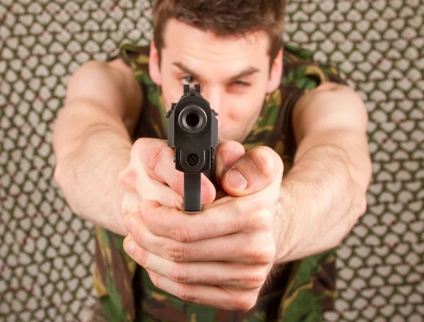 Soldado en chaleco de camuflaje sostiene un arma — Foto de Stock