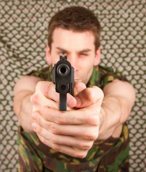 Soldier in camouflage vest is holding a gun — Stock Photo, Image