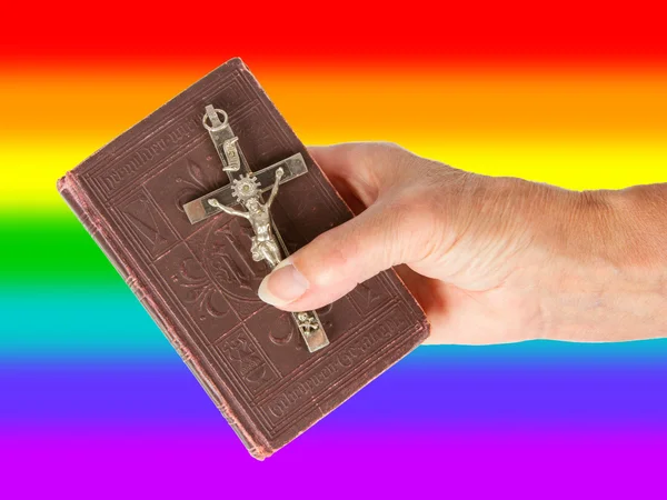 Old hand (woman) holding a very old bible, rainbow flag — Stock Photo, Image