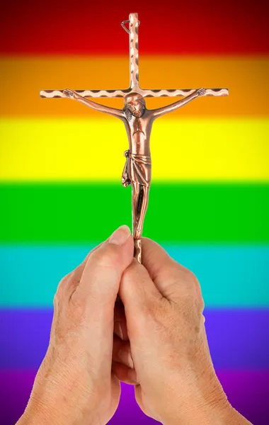 Old woman with catholic crucifix, isolated, rainbow flag pattern — Stock Photo, Image