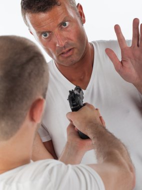 Scared man being threatened by a man with a handgun