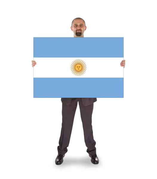 アルゼンチンの旗の大きなカードを保持しているビジネスマンの笑みを浮かべてください。 — ストック写真