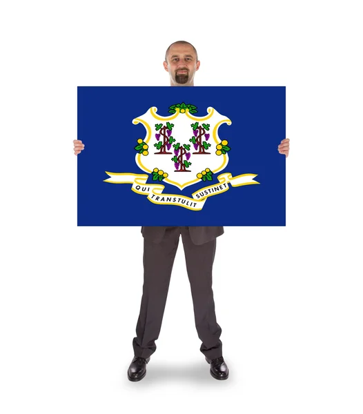 Un hombre de negocios sonriente sosteniendo una tarjeta grande, bandera de Connecticut — Foto de Stock