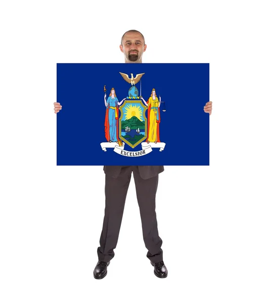 Un hombre de negocios sonriente sosteniendo una tarjeta grande, bandera de Nueva York — Foto de Stock