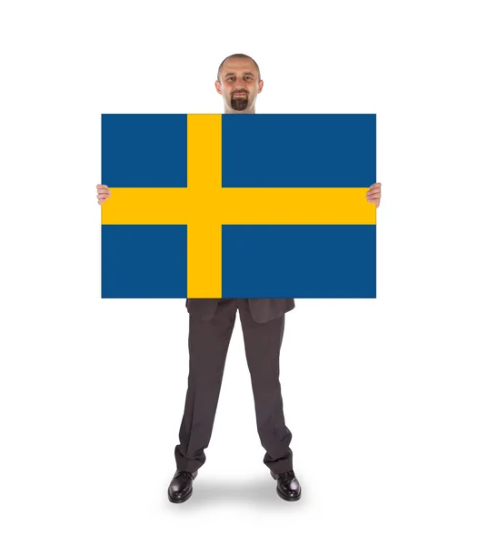 Un hombre de negocios sonriente sosteniendo una tarjeta grande, bandera de Suecia — Foto de Stock