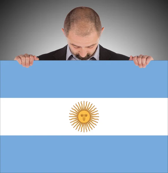 Smiling businessman holding a big card, flag of Argentine — Stock Photo, Image