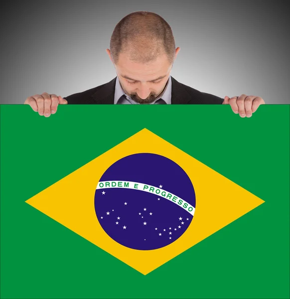 Smiling businessman holding a big card, flag of Brazil — Stock Photo, Image