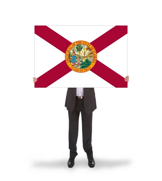 フロリダ州の旗の大きなカードを保持しているビジネスマンの笑みを浮かべてください。 — ストック写真