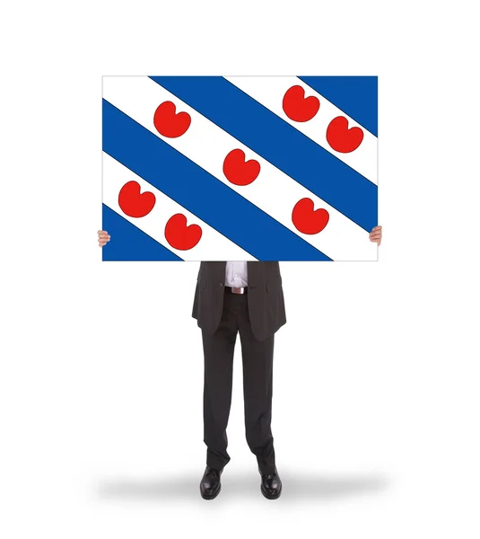 Hombre de negocios sonriente sosteniendo una tarjeta grande, bandera del holandés probando — Foto de Stock
