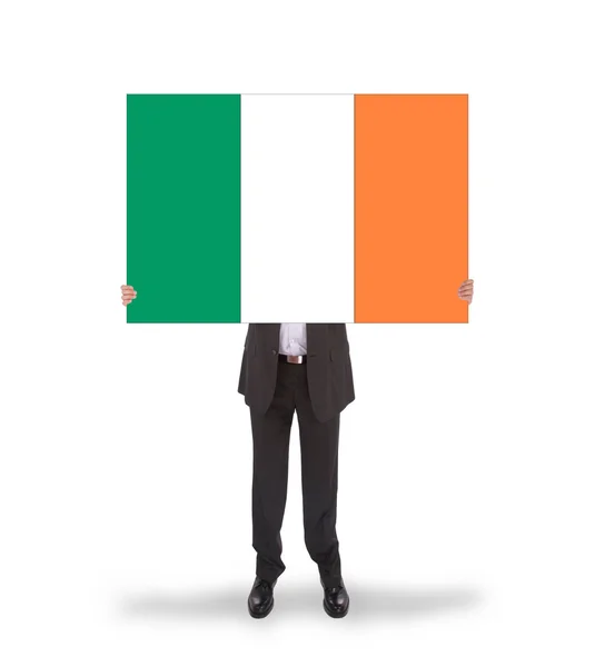 Empresário sorridente segurando um cartão grande, bandeira da Irlanda — Fotografia de Stock