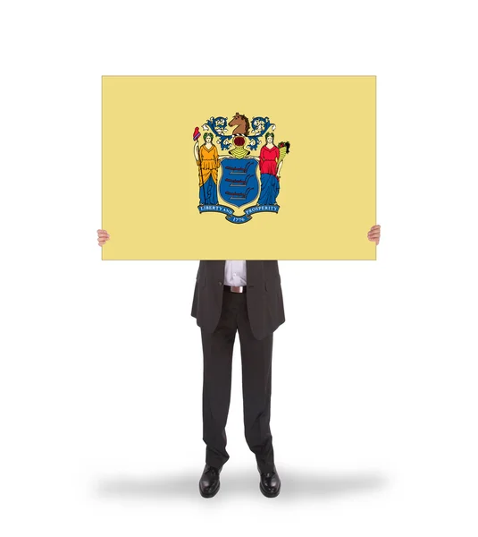 ニュージャージー州の旗の大きなカードを保持しているビジネスマンの笑みを浮かべてください。 — ストック写真