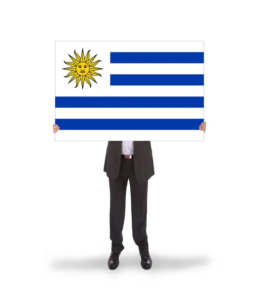 Leende affärsman håller ett stort kort, flagga uruguay — Stockfoto