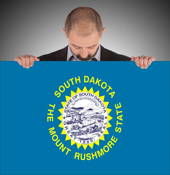 Un hombre de negocios sonriente sosteniendo una tarjeta grande, bandera de Dakota del Sur — Foto de Stock