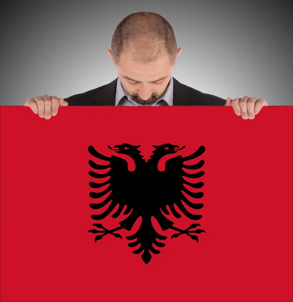 Businessman holding a big card, flag of Albania — Stock Photo, Image